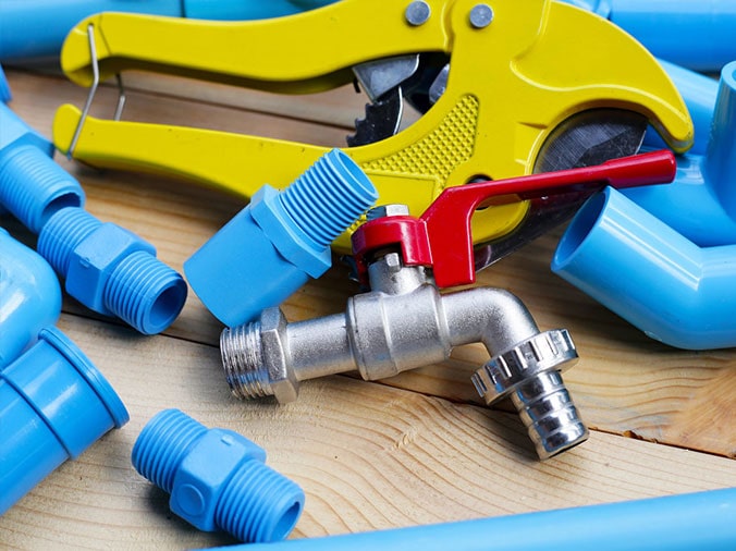 blue pvc plumbing fittings and a pvc cutting tool