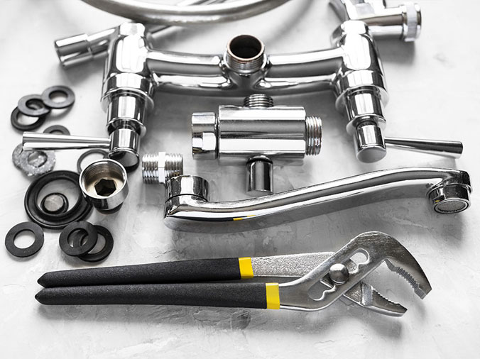 disassembled kitchen sink faucet with polished chrome finish and a plumbers wrench